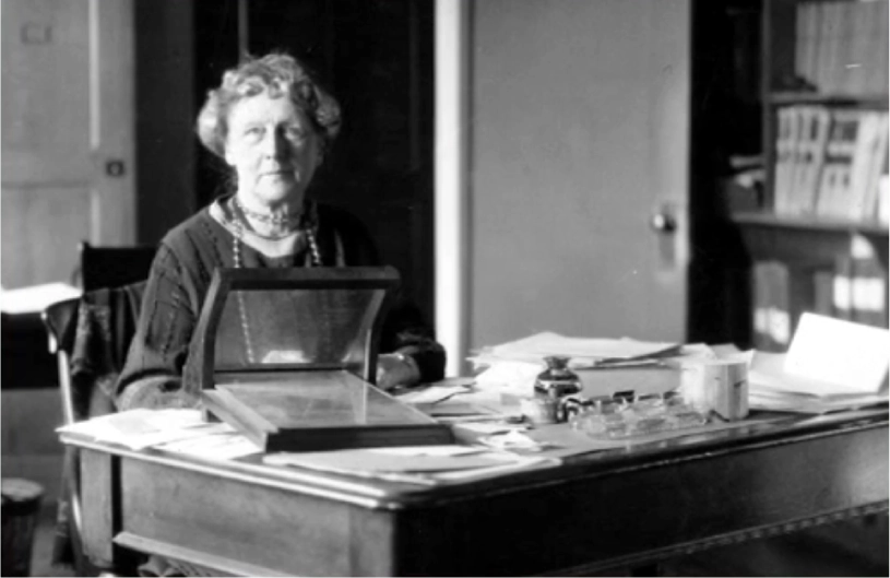 Black-and-white photo. Woman sits at a desk